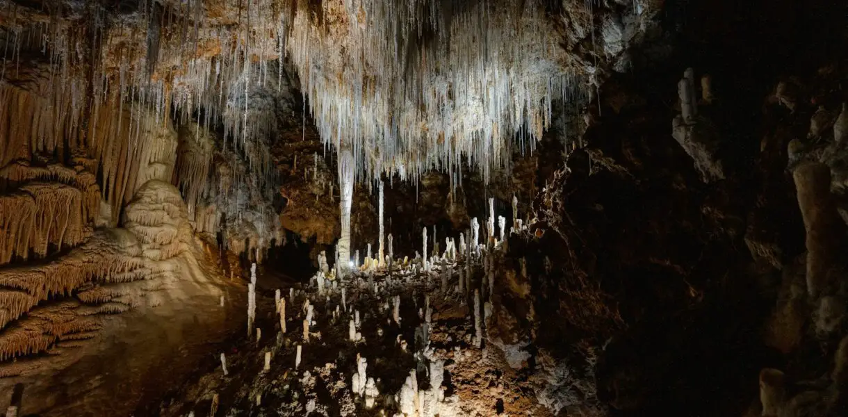 A cave filled with lots of ice hanging from the ceiling