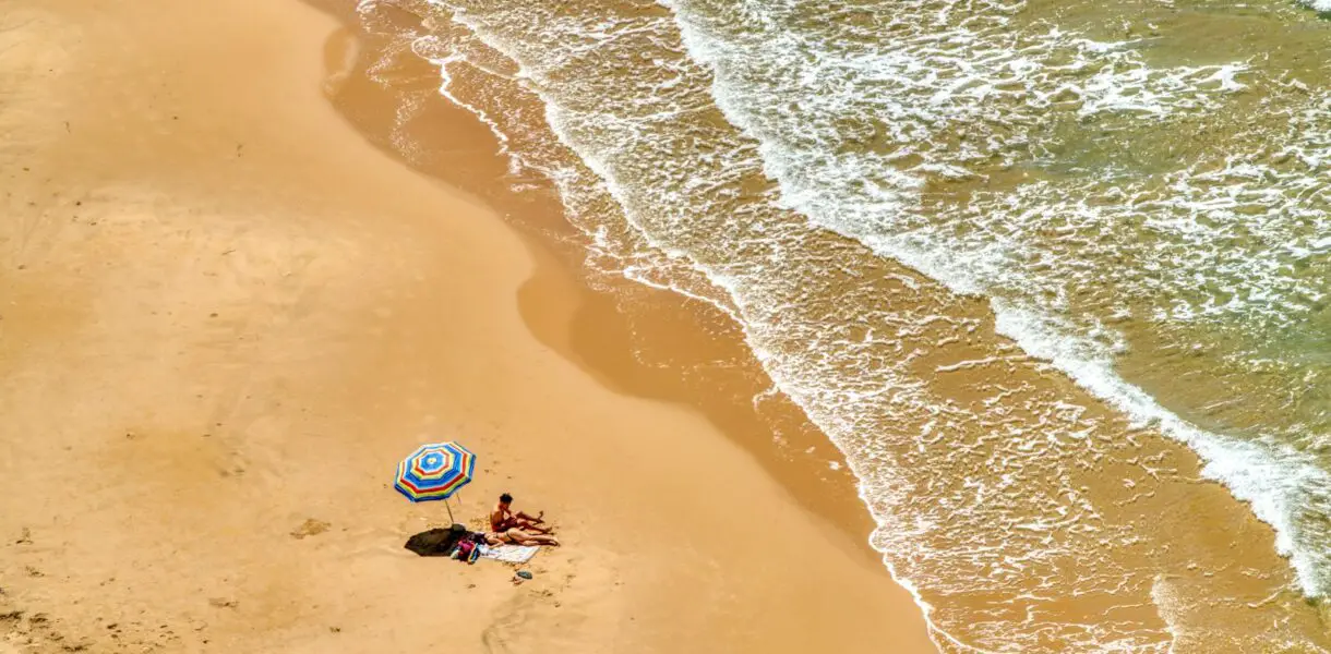 person in blue and white wetsuit riding blue and white surfboard on beach during daytime