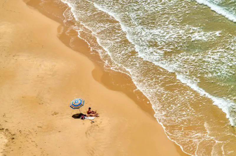 person in blue and white wetsuit riding blue and white surfboard on beach during daytime