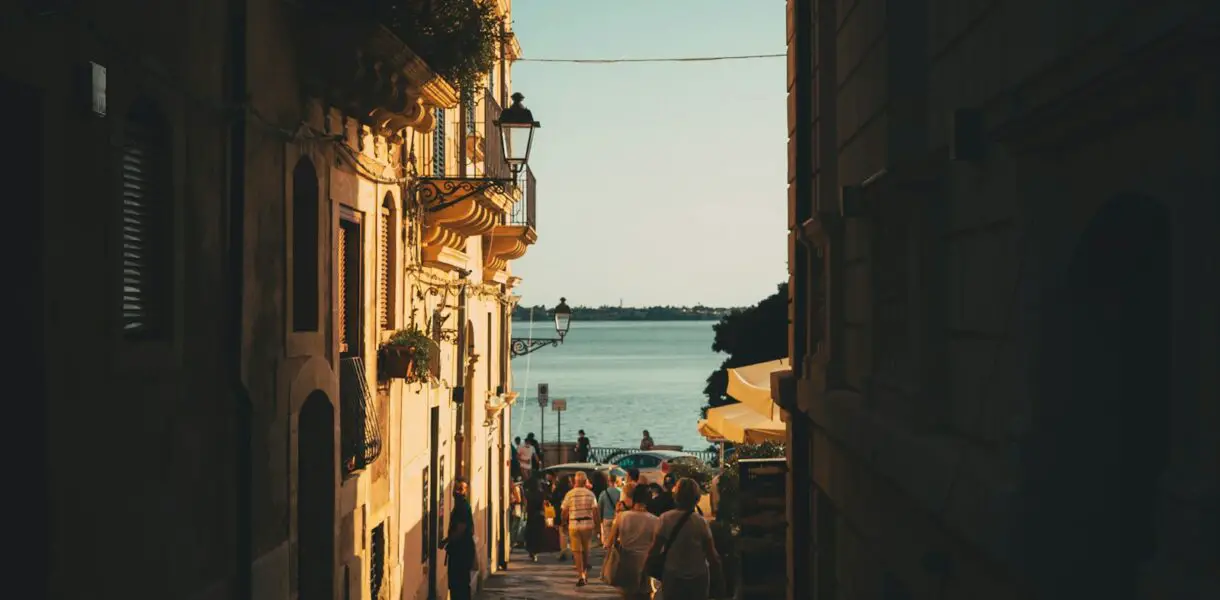 a group of people walking down a street next to a body of water