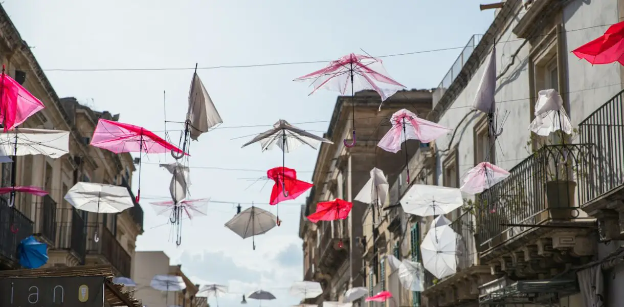 a city street filled with lots of pink and white umbrellas