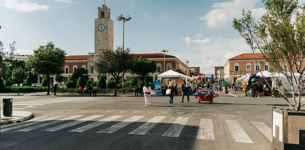 a group of people walking down a street next to a clock tower