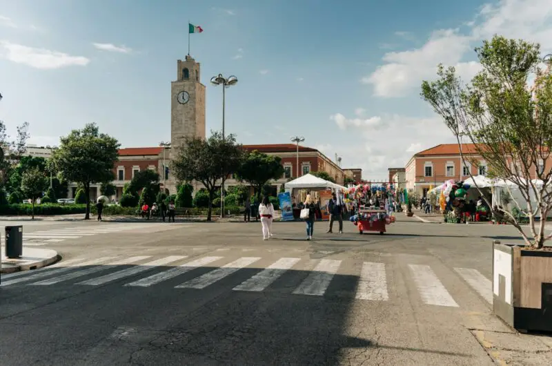 a group of people walking down a street next to a clock tower