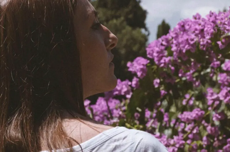 a woman looking at a flower