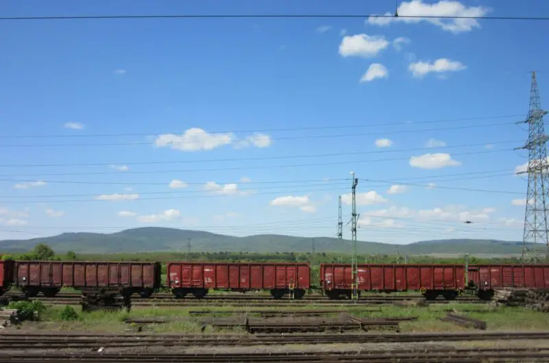 A red train traveling down train tracks next to a lush green field